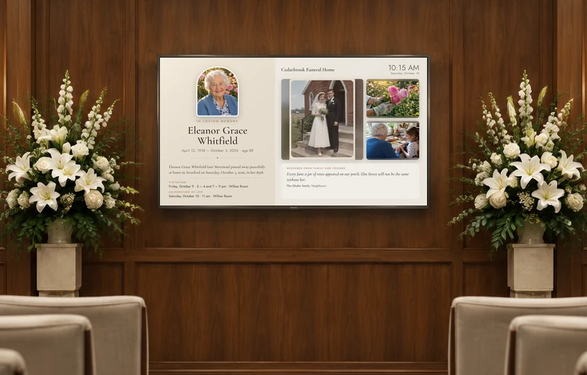 A funeral home visitation room: white lilies either side of a TV showing Eleanor Grace Whitfield’s memorial, with her portrait, her obituary, the service times and family photos
